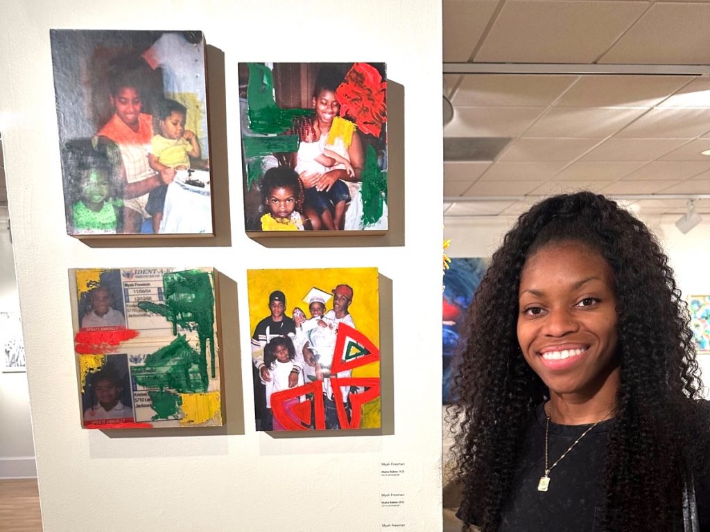 A photo of Myha Freeman standing in front of her work.